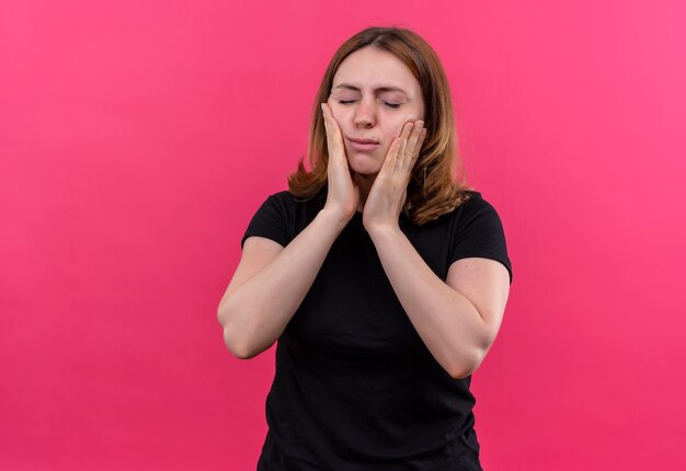 Foto gratuita mujer casual joven decepcionada poniendo las manos en las mejillas con los ojos cerrados en el espacio rosa aislado con espacio de copia