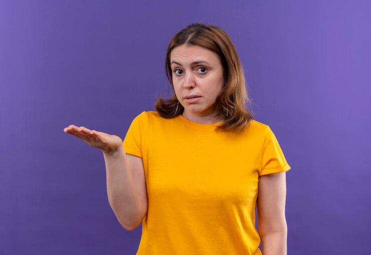 Foto gratuito mujer casual joven que muestra la mano vacía en la pared púrpura aislada