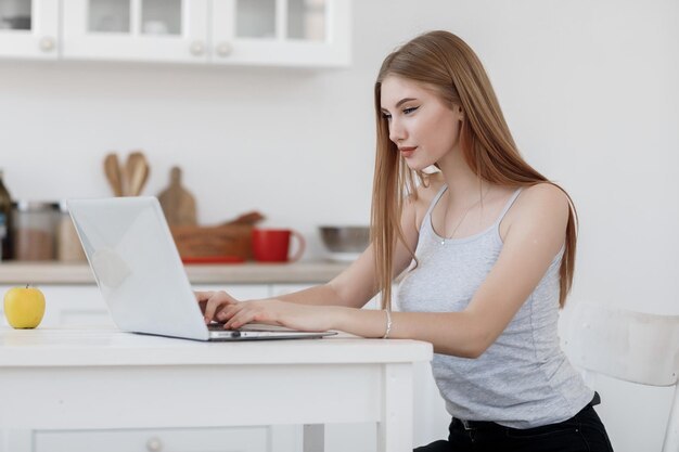 mujer casual joven que trabaja en casa en la computadora portátil