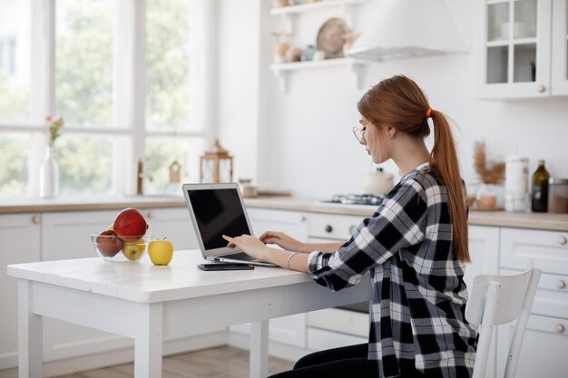 mujer casual joven que trabaja en casa en la computadora portátil