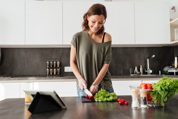 Mujer casual sonriente que hace la ensalada fresca