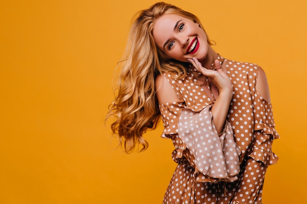 Mujer caucásica alegre con maquillaje de moda posando con sonrisa. Filmación en interiores de adorable dama blanca en ropa vintage.