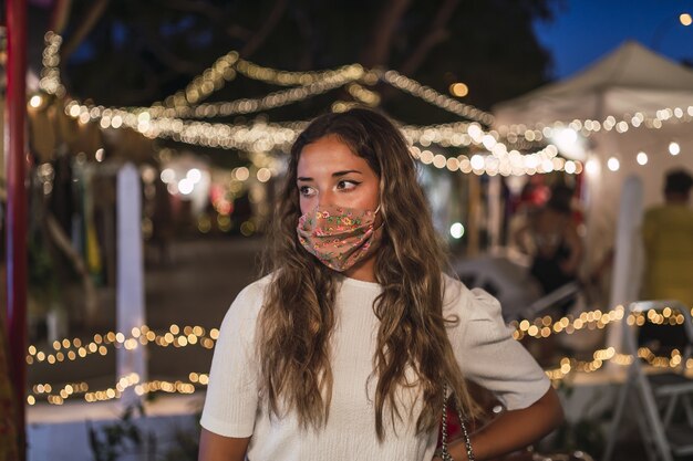 Mujer caucásica bronceada vistiendo una máscara floral en un parque de atracciones