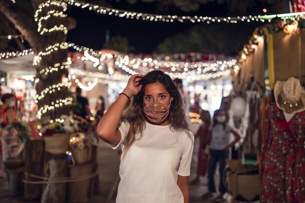 Mujer caucásica bronceada vistiendo una máscara floral en un parque de atracciones