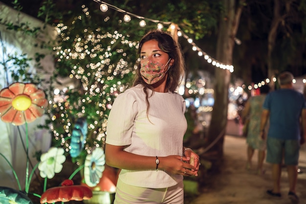 Foto gratuita mujer caucásica bronceada vistiendo una máscara floral en un parque de atracciones