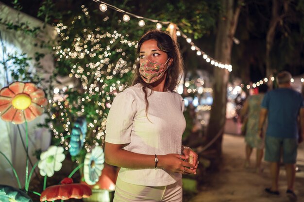 Mujer caucásica bronceada vistiendo una máscara floral en un parque de atracciones