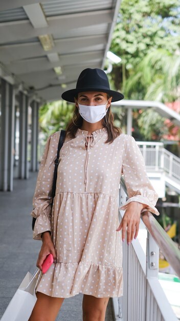 Mujer caucásica caminando en el cruce del metro en mascarilla médica mientras la pandemia en la ciudad de Bangkok.