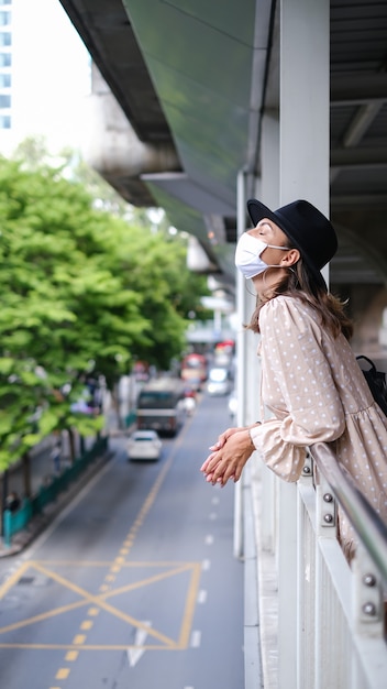 Mujer caucásica caminando en el cruce del metro en mascarilla médica mientras la pandemia en la ciudad de Bangkok.