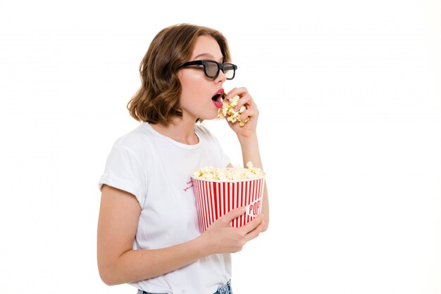 Mujer caucásica concentrada que sostiene la película del reloj de las palomitas de maíz.