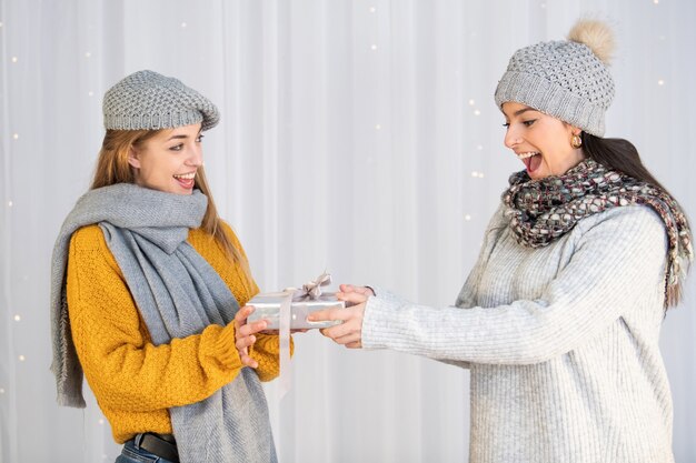 Mujer caucásica dando un regalo de Navidad a su amiga