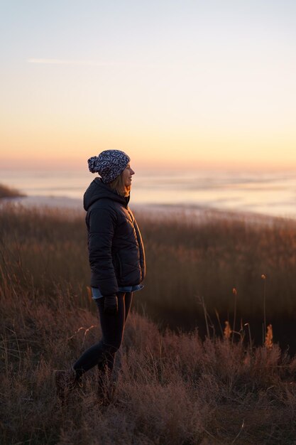 Mujer caucásica disfrutando de la vista de la naturaleza al aire libre por la noche viendo la puesta de sol