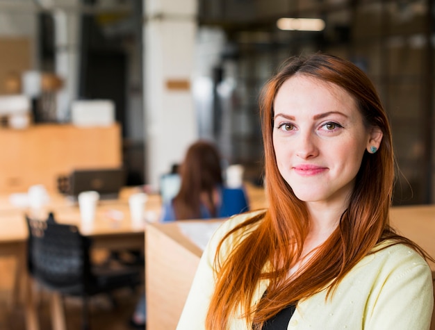 Mujer caucásica hermosa sonriente en la oficina que mira la cámara