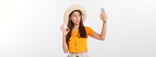 Mujer caucásica joven disfrutando del selfie con ella misma aislada sobre fondo blanco viajes de verano co