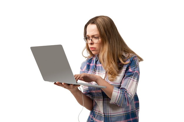 Mujer caucásica joven que usa la computadora portátil, dispositivos, aparatos aislados en el fondo blanco del estudio. Copyspace