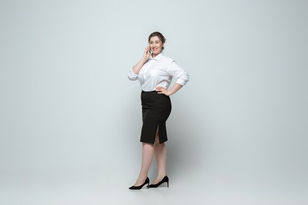 Mujer caucásica joven en ropa de sport en gris. Personaje femenino corporal positivo, talla grande