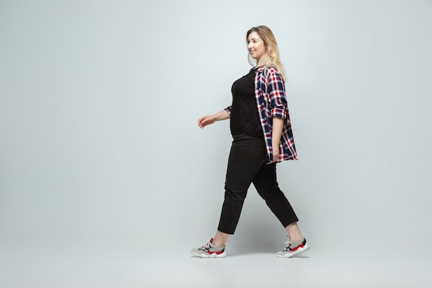 Mujer caucásica joven en ropa de sport en gris. Personaje femenino corporal positivo, talla grande