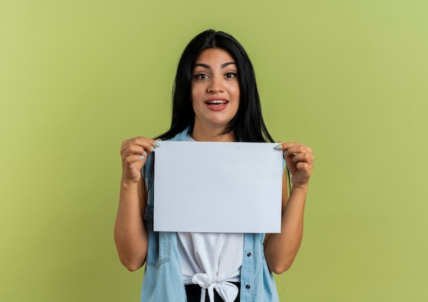 Mujer caucásica joven sorprendida sostiene la hoja de papel