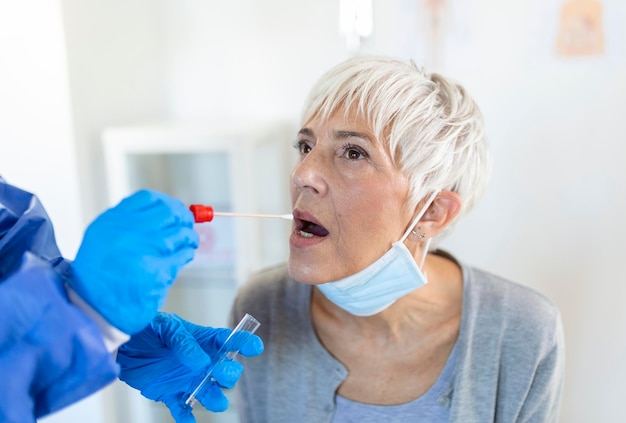 Foto gratuita mujer caucásica madura en un entorno clínico siendo examinada por un trabajador de la salud con atuendo protector para determinar si ha contraído el coronavirus o covid19