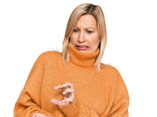 Mujer caucásica de mediana edad con suéter de invierno casual expresión disgustada disgustada y temerosa haciendo cara de disgusto porque la reacción de aversión