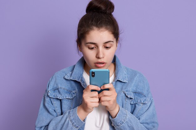 Mujer caucásica mirando atentamente la pantalla de su dispositivo con expresión facial asombrada