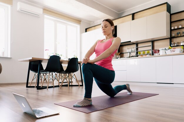 Mujer caucásica practicando yoga en casa