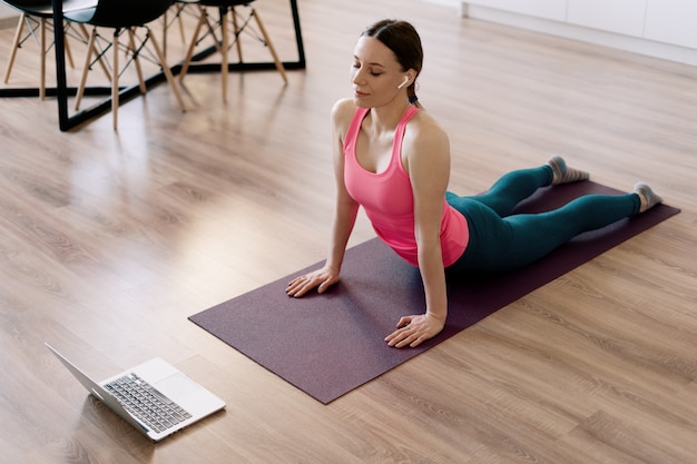 Mujer caucásica practicando yoga en casa