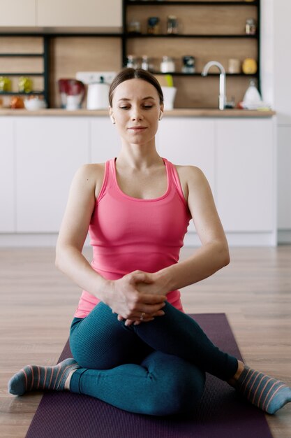 Mujer caucásica practicando yoga en casa