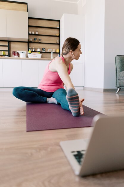 Mujer caucásica practicando yoga en casa