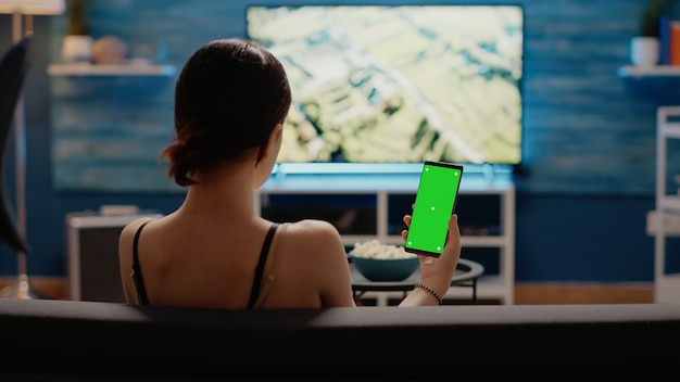 Mujer caucásica sosteniendo teléfono móvil con pantalla verde