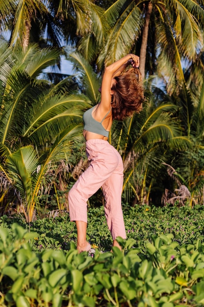 Mujer caucásica tatuada en pantalón rosa y top verde de moda