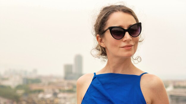 Mujer caucásica en vestido azul con vista de Barcelona al fondo, España