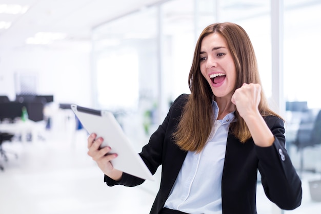 Mujer celebrando mientras mira una tablet