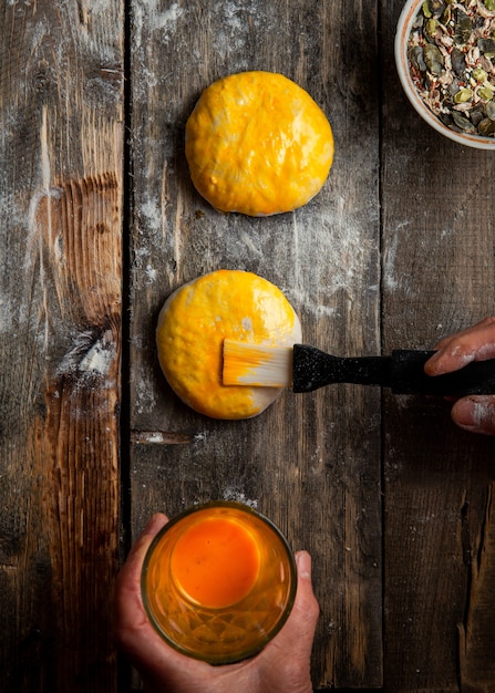 Mujer cepillando la masa con yema de huevo antes de hornear vista superior