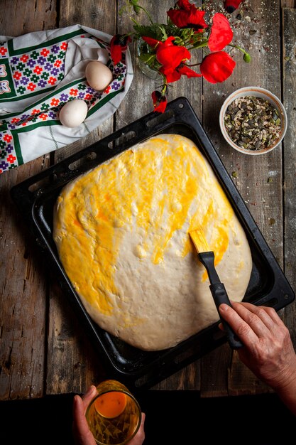 Mujer cepillando la masa con yema de huevo vista superior