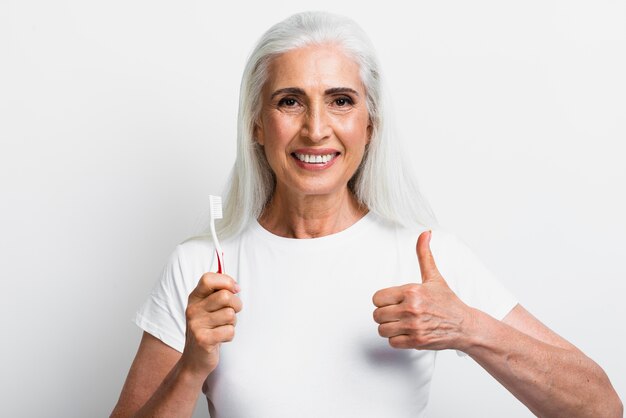 Mujer con cepillo de dientes con el pulgar hacia arriba