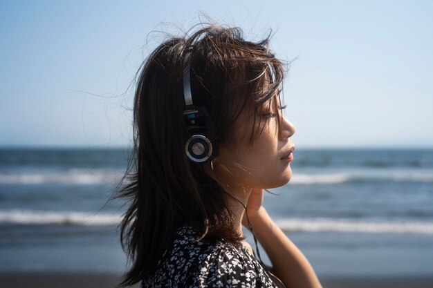 Mujer de cerca con auriculares en la playa