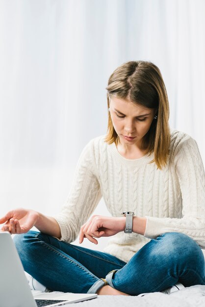 Mujer cerca de la computadora portátil mirando el reloj