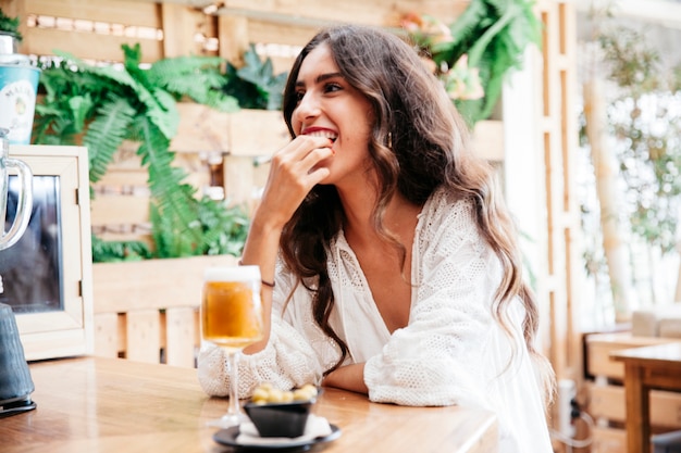 Mujer con cerveza comiendo aceitunas