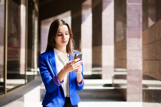 Mujer en chaqueta azul verifica su teléfono