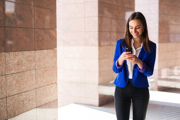 Foto gratuita mujer en chaqueta azul verifica su teléfono