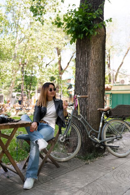 Mujer con chaqueta de cuero sintético sentada en una mesa al aire libre