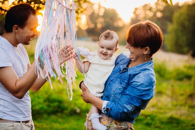 La mujer en la chaqueta de jeans sostiene a la niña mientras el padre juega con ella