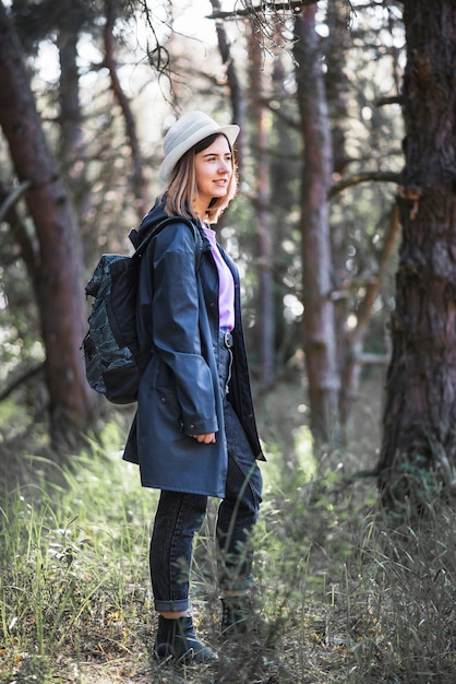 Mujer en chaqueta de pie en el bosque