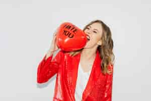 Foto gratuita mujer con chaqueta roja mordiendo un globo rojo con el texto i hate you