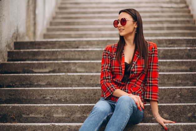 Mujer en chaqueta roja sentada en las escaleras