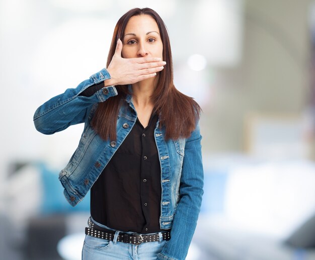 Mujer con chaqueta vaquera tapándose la boca