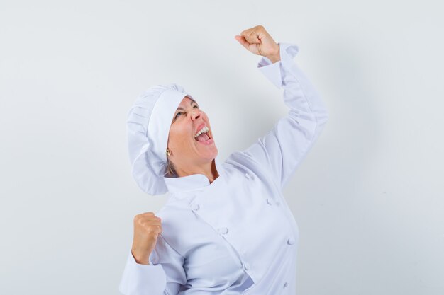 mujer chef mostrando gesto de ganador en uniforme blanco y con suerte.