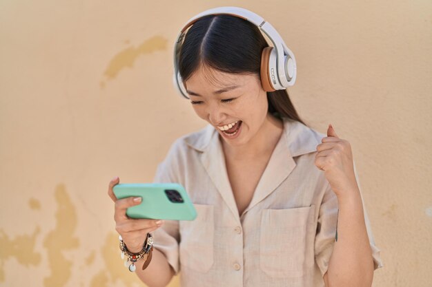 Mujer china sonriendo confiada jugando videojuegos sobre fondo blanco aislado