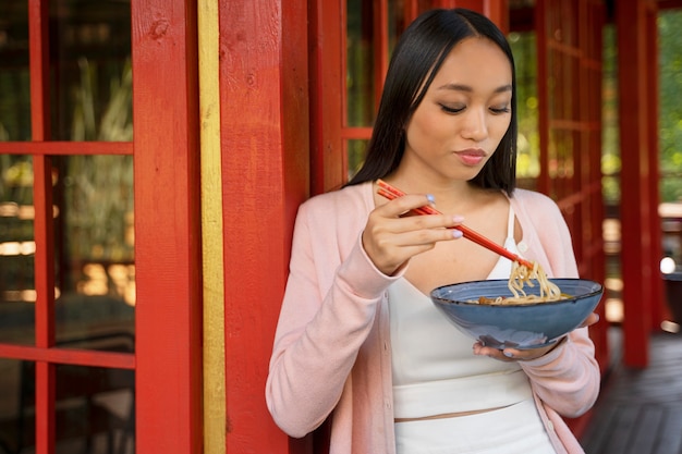 Mujer china de tiro medio comiendo fideos