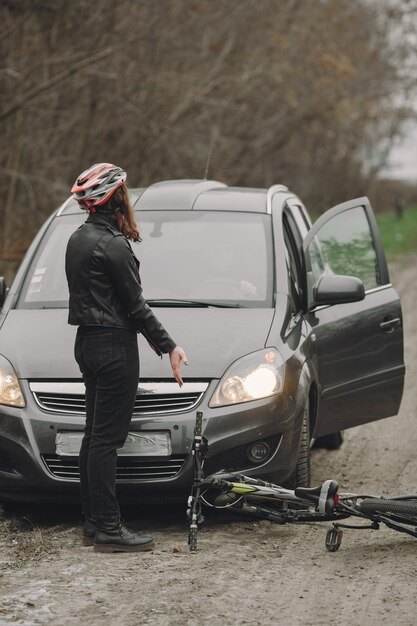 La mujer chocó contra el auto. Chica con casco. La gente discute por el accidente.